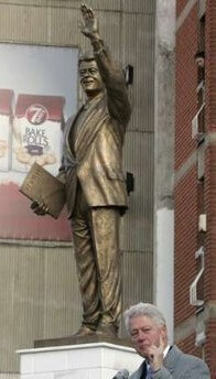 Statue of Bill Clinton waving at a cute Albanian chick with his left hand while holding his little black book in his right hand